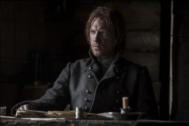 Scene from The Revenant (2015). Domnhall Gleeson as Andrew Henry, sitting at a table inside the movie's version of Fort Kiowa.