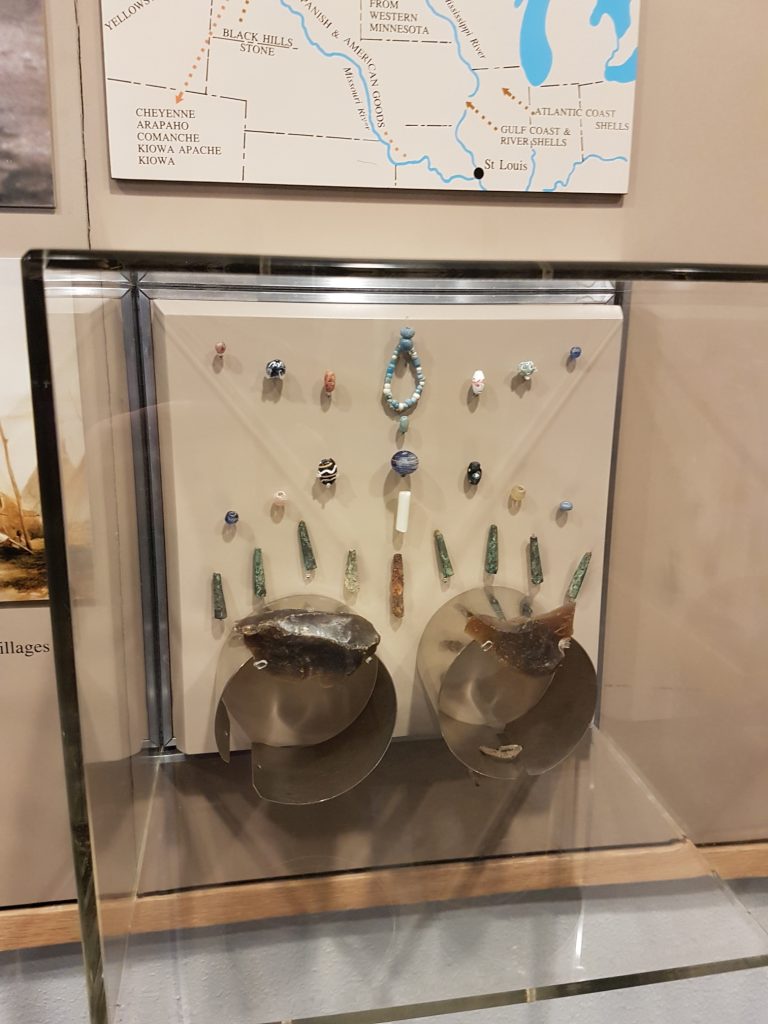 Glass display case with pieces of Knife River flint, glass beads, and metal tinklers. No text.