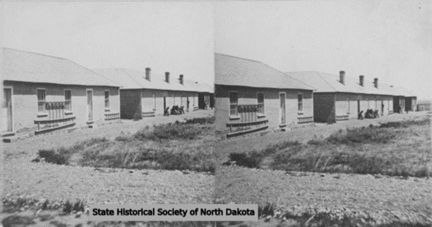 Black-and-white image of two single-story buildings standing side by side in a sunny landscape. 