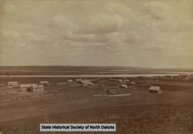 Sepia landscape. Scattered houses on flat land by the river under a cloudy sky.